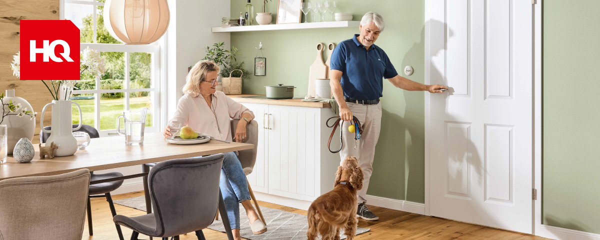 Ehepaar mit Hund in einer hellgrün gestrichenen Küche mit weißer Tür